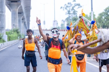 Gaziabad, Uttar Pradesh, Hindistan - 31 Temmuz 2024: Sawan Shivratri sırasında çıplak ayakla Kanwar Yatra 'yı seslendiren Hindu hacıların portresi ve Hindu tanrısı Shiva' ya ibadet etmek için kutsal Ganga suyu taşımak.