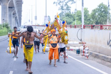 Gaziabad, Uttar Pradesh, Hindistan - 31 Temmuz 2024: Sawan Shivratri sırasında çıplak ayakla Kanwar Yatra 'yı seslendiren Hindu hacıların portresi ve Hindu tanrısı Shiva' ya ibadet etmek için kutsal Ganga suyu taşımak.