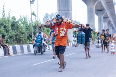 Gaziabad, Uttar Pradesh, Hindistan - 31 Temmuz 2024: Sawan Shivratri sırasında çıplak ayakla Kanwar Yatra 'yı seslendiren Hindu hacıların portresi ve Hindu tanrısı Shiva' ya ibadet etmek için kutsal Ganga suyu taşımak.