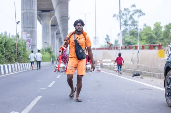 stock image Ghaziabad, Uttar Pradesh, India - July 31 2024: Portrait of Hindu pilgrim performing Kanwar Yatra barefoot during Sawan Shivratri and carrying holy ganga water to worship Hindu god Shiva with rituals.