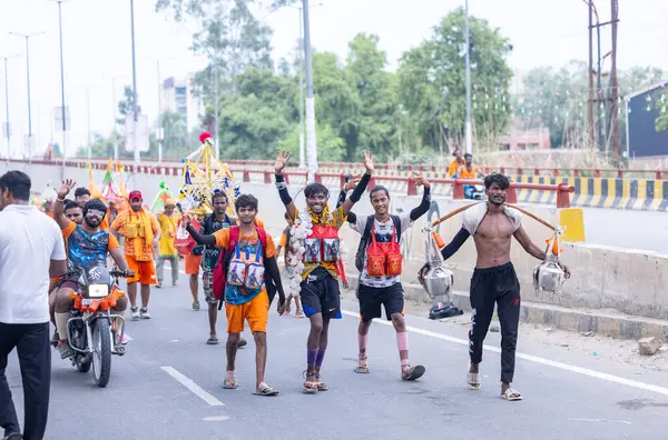 Gaziabad, Uttar Pradesh, Hindistan - 31 Temmuz 2024: Hindu hacıların Sawan Shivratri sırasında yürüyerek Kanwar Yatra 'yı sahneleyen ve Hindu tanrısı Shiva' ya ibadet etmek için kutsal Ganga suyu taşıyan portresi.