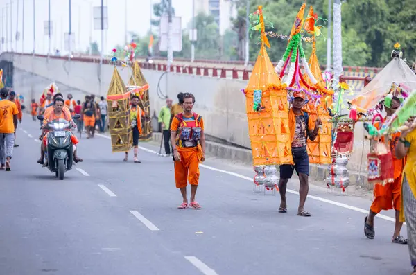 Gaziabad, Uttar Pradesh, Hindistan - 31 Temmuz 2024: Sawan Shivratri sırasında çıplak ayakla Kanwar Yatra 'yı seslendiren Hindu hacıların portresi ve Hindu tanrısı Shiva' ya ibadet etmek için kutsal Ganga suyu taşımak.