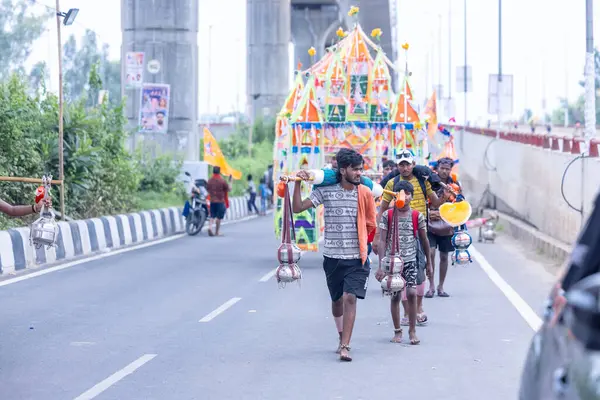 Gaziabad, Uttar Pradesh, Hindistan - 31 Temmuz 2024: Sawan Shivratri sırasında çıplak ayakla Kanwar Yatra 'yı seslendiren Hindu hacıların portresi ve Hindu tanrısı Shiva' ya ibadet etmek için kutsal Ganga suyu taşımak.