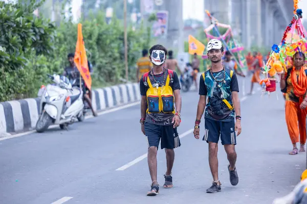 Gaziabad, Uttar Pradesh, Hindistan - 31 Temmuz 2024: Sawan Shivratri sırasında çıplak ayakla Kanwar Yatra 'yı seslendiren Hindu hacıların portresi ve Hindu tanrısı Shiva' ya ibadet etmek için kutsal Ganga suyu taşımak.