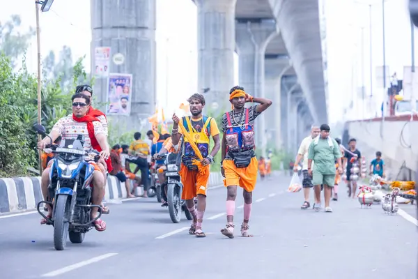 Gaziabad, Uttar Pradesh, Hindistan - 31 Temmuz 2024: Hindu hacıların Sawan Shivratri sırasında yürüyerek Kanwar Yatra 'yı sahneleyen ve Hindu tanrısı Shiva' ya ibadet etmek için kutsal Ganga suyu taşıyan portresi.