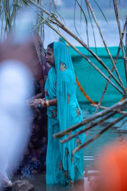 Gaziabad, Uttar Pradesh, Hindistan - 19 Kasım 2023: Chhas Puja, Hintli Hintli kadın dindarların portresi, gün batımında güneş tanrısı güneşe ibadet etmek için nehirde durarak Chhas puja ayini yapıyorlar..