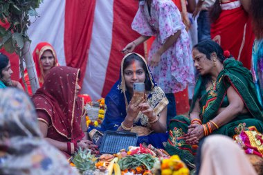 Gaziabad, Uttar Pradesh, Hindistan - 19 Kasım 2023: Chhas Puja, bir grup Hintli kadın geleneksel etnik kıyafetlerle chhas puja ayinlerini gerçekleştirmek için zemin üzerinde oturuyorlar.