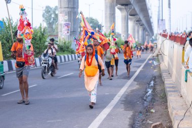 Gaziabad, Uttar Pradesh, Hindistan - 1 Ağustos 2024: Bir grup Hindu hacı Sawan shivratri sırasında Kanwar yatra 'yı sahnelerken ve Tanrı' ya ibadet etmek için kutsal kenevir suyu taşırken.