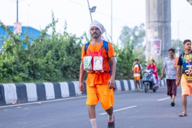 Gaziabad, Uttar Pradesh, Hindistan - 31 Ağustos 2024: Sawan shivratri sırasında çıplak ayakla kanwar yatra yapan Hindu hacı portresi ve Hindu tanrılarına ibadet etmek için kutsal kenevir suyu taşımak