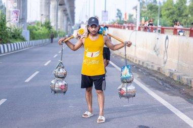 Gaziabad, Uttar Pradesh, Hindistan - 31 Ağustos 2024: Sawan shivratri sırasında çıplak ayakla kanwar yatra yapan Hindu hacı portresi ve Hindu tanrılarına ibadet etmek için kutsal kenevir suyu taşımak