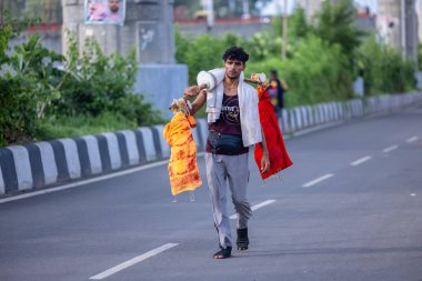 Gaziabad, Uttar Pradesh, Hindistan - 31 Ağustos 2024: Sawan shivratri sırasında çıplak ayakla kanwar yatra yapan Hindu hacı portresi ve Hindu tanrılarına ibadet etmek için kutsal kenevir suyu taşımak