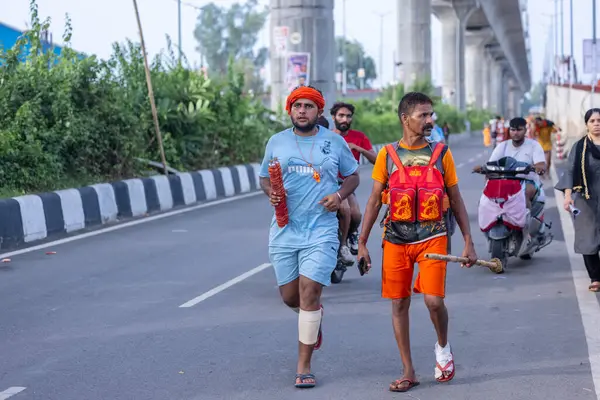 Gaziabad, Uttar Pradesh, Hindistan - 1 Ağustos 2024: Bir grup Hindu hacı Sawan shivratri sırasında Kanwar yatra 'yı sahnelerken ve Tanrı' ya ibadet etmek için kutsal kenevir suyu taşırken.