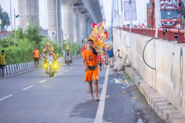 Gaziabad, Uttar Pradesh, Hindistan - 31 Ağustos 2024: Sawan shivratri sırasında çıplak ayakla kanwar yatra yapan Hindu hacı portresi ve Hindu tanrılarına ibadet etmek için kutsal kenevir suyu taşımak