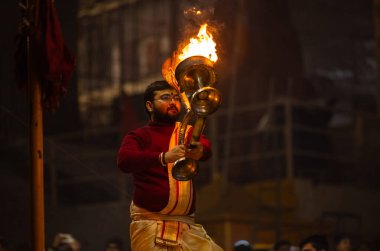 Varanasi, Uttar Pradesh, Hindistan - 18 Ocak 2024: Ganga aarti, Genç erkek rahibin portresi Dashashwamedh ghat 'ta kutsal nehir ganges akşam aarti gösterisi Hindu ayinleri ile geleneksel elbise. 