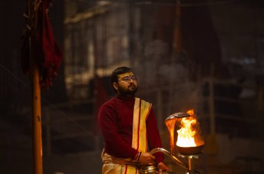 Varanasi, Uttar Pradesh, Hindistan - 18 Ocak 2024: Ganga aarti, Genç erkek rahibin portresi Dashashwamedh ghat 'ta kutsal nehir ganges akşam aarti gösterisi Hindu ayinleri ile geleneksel elbise. 