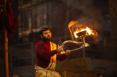 Varanasi, Uttar Pradesh, Hindistan - 18 Ocak 2024: Ganga aarti, Genç erkek rahibin portresi Dashashwamedh ghat 'ta kutsal nehir ganges akşam aarti gösterisi Hindu ayinleri ile geleneksel elbise. 