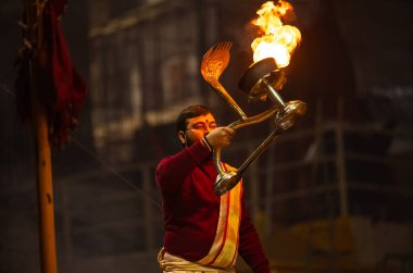 Varanasi, Uttar Pradesh, Hindistan - 18 Ocak 2024: Ganga aarti, Genç erkek rahibin portresi Dashashwamedh ghat 'ta kutsal nehir ganges akşam aarti gösterisi Hindu ayinleri ile geleneksel elbise. 