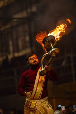 Varanasi, Uttar Pradesh, Hindistan - 18 Ocak 2024: Ganga aarti, Genç erkek rahibin portresi Dashashwamedh ghat 'ta kutsal nehir ganges akşam aarti gösterisi Hindu ayinleri ile geleneksel elbise. 