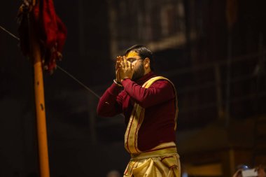 Varanasi, Uttar Pradesh, Hindistan - 18 Ocak 2024: Ganga aarti, Genç erkek rahibin portresi Dashashwamedh ghat 'ta kutsal nehir ganges akşam aarti gösterisi Hindu ayinleri ile geleneksel elbise. 