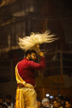 Varanasi, Uttar Pradesh, Hindistan - 18 Ocak 2024: Ganga aarti, Genç erkek rahibin portresi Dashashwamedh ghat 'ta kutsal nehir ganges akşam aarti gösterisi Hindu ayinleri ile geleneksel elbise. 