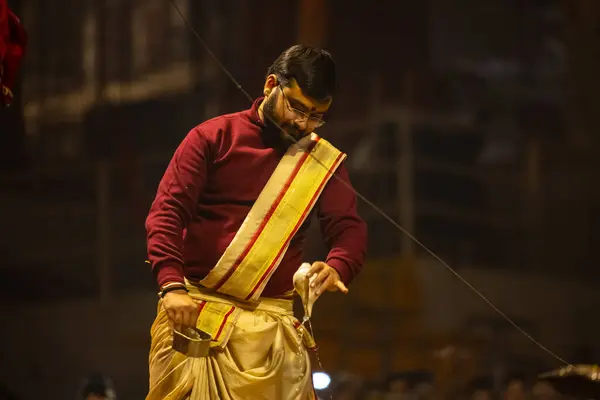 stock image Varanasi, Uttar Pradesh, India - January 18 2024: Ganga aarti, Portrait of young male priest performing holy river Ganges evening aarti at dashashwamedh ghat in traditional dress with Hindu rituals. 