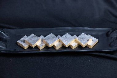 Kaju katli tatlıları arka planda servis tepsisinde.