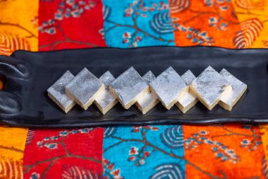 Kaju katli tatlıları arka planda servis tepsisinde.