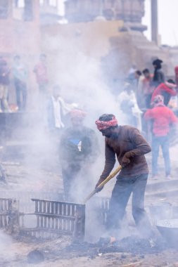 Varanasi, Uttar Pradesh, Hindistan - 18 Ocak 2024: Hintli bir erkek işçinin portresi yanmış kemikleri toplamak ve cesetleri hindu ayini olarak manikarnika ghat 'ta yakmak için yer açmak