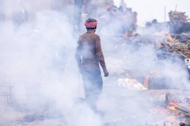 Varanasi, Uttar Pradesh, Hindistan - 18 Ocak 2024: Hintli bir erkek işçinin portresi yanmış kemikleri toplamak ve cesetleri hindu ayini olarak manikarnika ghat 'ta yakmak için yer açmak
