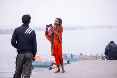 Varanasi, Uttar Pradesh, Hindistan - 18 Ocak 2024: Varanasi 'deki çetelerin yakınındaki ghat' larda yaşayan insanlar. Sadhu, Kaşhi 'de Ganga yakınlarında meditasyon yapıyor..