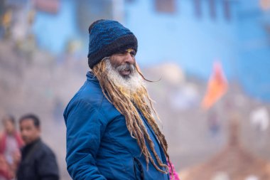 Varanasi, Uttar Pradesh, Hindistan - 18 Ocak 2024: Varanasi 'deki çetelerin yakınındaki ghatlarda yürüyen geleneksel sadhu baba resmi. Sadhu, Kaşhi 'de Ganga yakınlarında meditasyon yapıyor.