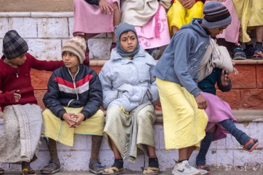 Varanasi, Uttar Pradesh, India - January 18 2024: Group of an young students of gurukul or school at ghats of holy river ganga in varanasi during winter morning. clipart