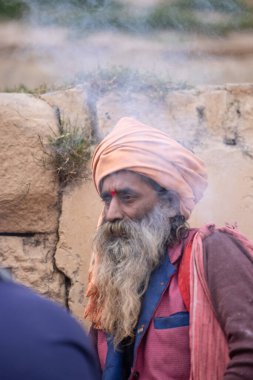 Varanasi, Uttar Pradesh, Hindistan - 18 Ocak 2024: Chlam veya puro içen yaşlı bir erkek sadhu 'nun portresi.