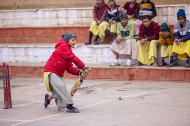 Varanasi, Uttar Pradesh, Hindistan - 18 Ocak 2024: Gurukul okulunun Hintli öğrencileri kış sabahı arkadaşlarıyla birlikte Varanasi 'de nehir keneviri ghatlarında kriket oynuyorlar.