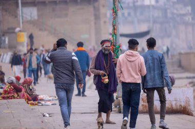 Varanasi, Uttar Pradesh, Hindistan - 18 Ocak 2024: Varanasi 'deki çetelerin yakınındaki ghat' larda yaşayan insanlar. Sadhu, Kaşhi 'de Ganga yakınlarında meditasyon yapıyor..