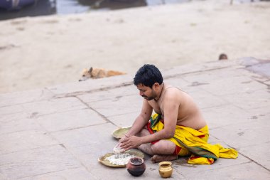 Varanasi, Uttar Pradesh, India - January 18 2024: brahmin south indian people performing shraadh rituals at kedar ghat under the supervision of priest near river ganges in varanasi. clipart