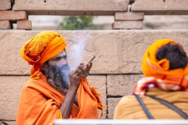 Varanasi, Uttar Pradesh, Hindistan - 18 Ocak 2024: Chlam veya puro içen yaşlı bir erkek sadhu 'nun portresi.