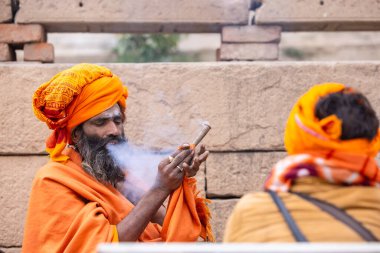 Varanasi, Uttar Pradesh, Hindistan - 18 Ocak 2024: Chlam veya puro içen yaşlı bir erkek sadhu 'nun portresi.