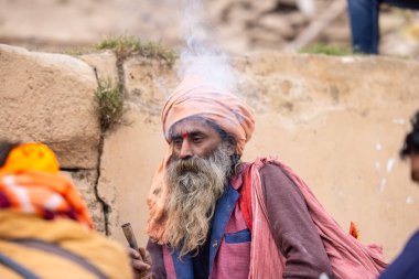 Varanasi, Uttar Pradesh, Hindistan - 18 Ocak 2024: Chlam veya puro içen yaşlı bir erkek sadhu 'nun portresi.