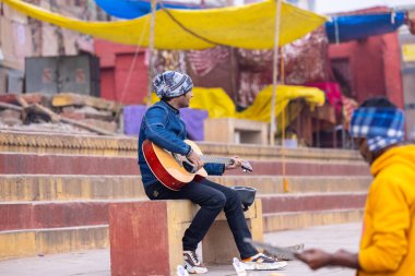 Varanasi, Uttar Pradesh, Hindistan - 05 Mart 2023: Varanasi 'deki çetelerin yakınındaki ghatlarda geleneksel giysiler giyen insanlar.