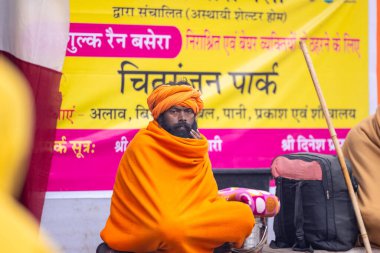 Varanasi, Uttar Pradesh, Hindistan - 19 Ocak 2024: Varanasi 'deki çetelerin yakınındaki ghatlarda yürüyen geleneksel sadhu elbiseli yaşlı bir adamın portresi.