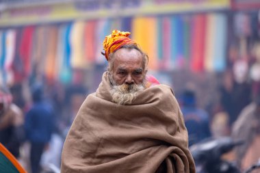 Varanasi, Uttar Pradesh, Hindistan - 19 Ocak 2024: Varanasi 'deki çetelerin yakınındaki ghatlarda yürüyen geleneksel sadhu elbiseli yaşlı bir adamın portresi.