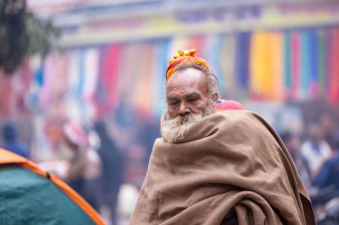 Varanasi, Uttar Pradesh, Hindistan - 19 Ocak 2024: Varanasi 'deki çetelerin yakınındaki ghatlarda yürüyen geleneksel sadhu elbiseli yaşlı bir adamın portresi.