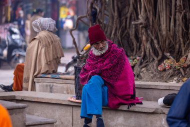 Varanasi, Uttar Pradesh, Hindistan - 19 Ocak 2024: Varanasi 'deki çetelerin yakınındaki ghatlarda yürüyen geleneksel sadhu elbiseli yaşlı bir adamın portresi.