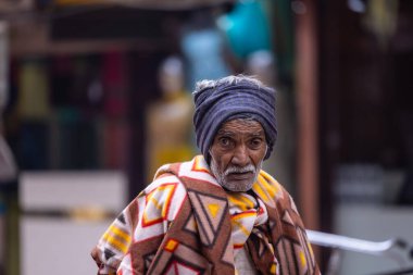 Varanasi, Uttar Pradesh, Hindistan - 19 Ocak 2024: Varanasi 'deki çetelerin yakınındaki ghatlarda yürüyen geleneksel sadhu elbiseli yaşlı bir adamın portresi.