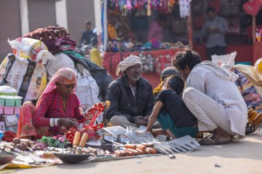 Puşkar, Rajasthan, Hindistan - 25 Kasım 2023: Puşkar Fuarı, Rajasthan 'lı Hintli bir kadının portresi, geleneksel renkli elbiseler ve başörtüsü ile sokak fuarında ürünler satışı.