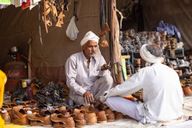 Puşkar, Rajasthan, Hindistan - 25 Kasım 2023: Puşkar Fuarı, Rajasthan 'lı Hintli bir kadının portresi, geleneksel renkli elbiseler ve başörtüsü ile sokak fuarında ürünler satışı.