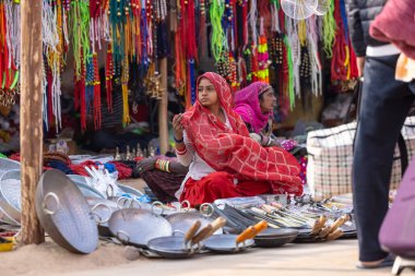 Puşkar, Rajasthan, Hindistan - 25 Kasım 2023: Puşkar Fuarı, Rajasthan 'lı Hintli bir kadının portresi, geleneksel renkli elbiseler ve başörtüsü ile sokak fuarında ürünler satışı.