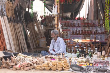 Puşkar, Rajasthan, Hindistan - 25 Kasım 2023: Puşkar Fuarı, Rajasthan 'lı Hintli bir kadının portresi, geleneksel renkli elbiseler ve başörtüsü ile sokak fuarında ürünler satışı.
