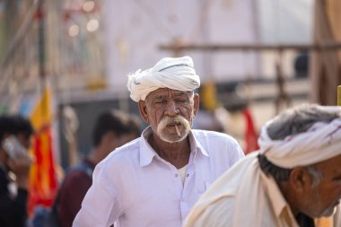 Puşkar, Rajasthan, Hindistan - 25 Kasım 2023: Puşkar Fuarı, Rajasthani 'li yaşlı bir erkeğin portresi geleneksel elbise ve renkli türbanlı bir adam.